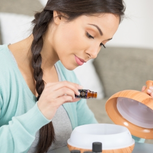Woman Pouring Lavender Essential Oil in Diffuser